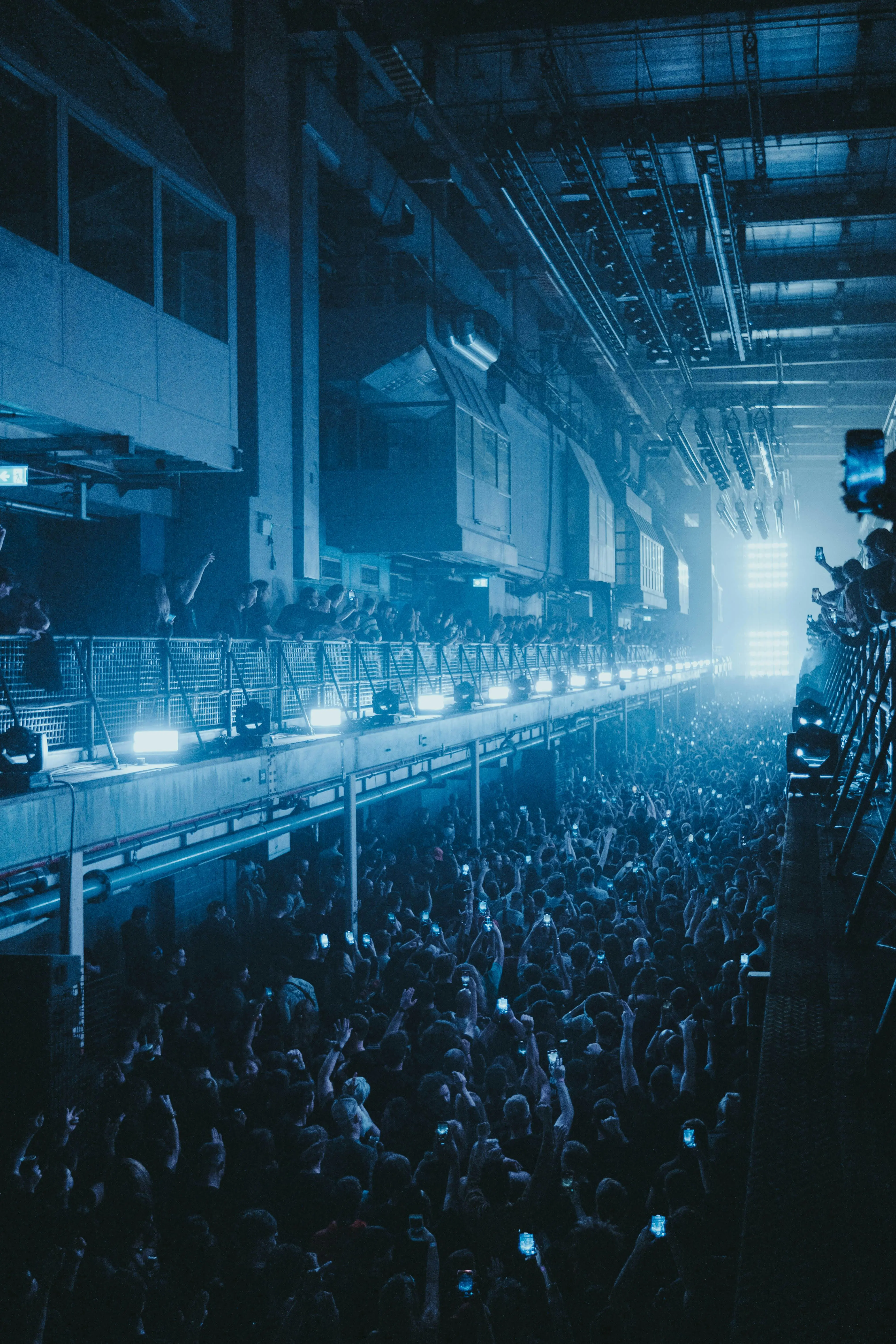 A rave in an industrial warehouse with a balcony